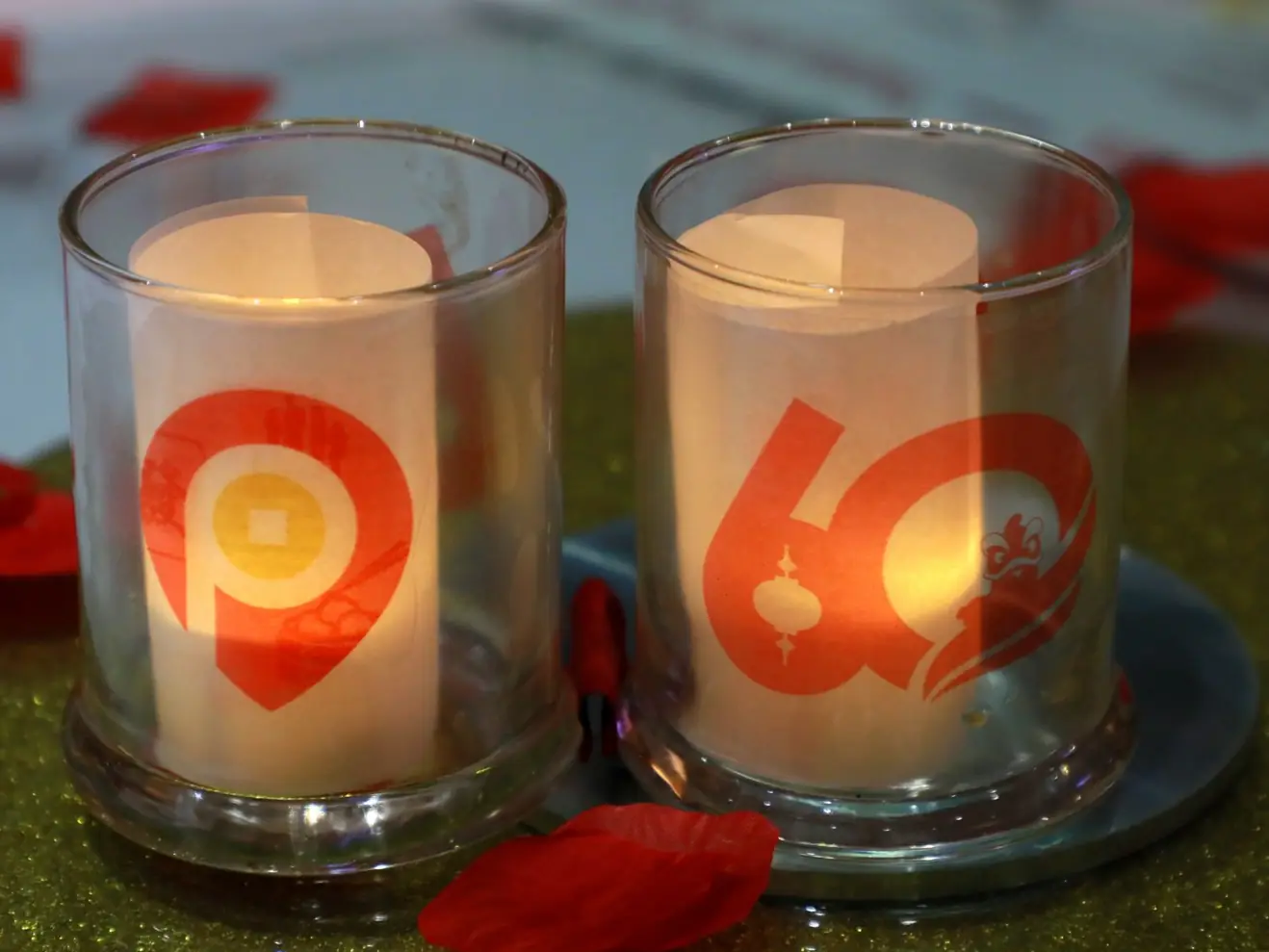 Two commemorative votive candles, one with the Portsmouth Square Garage logo and one with the 60th-anniversary emblem