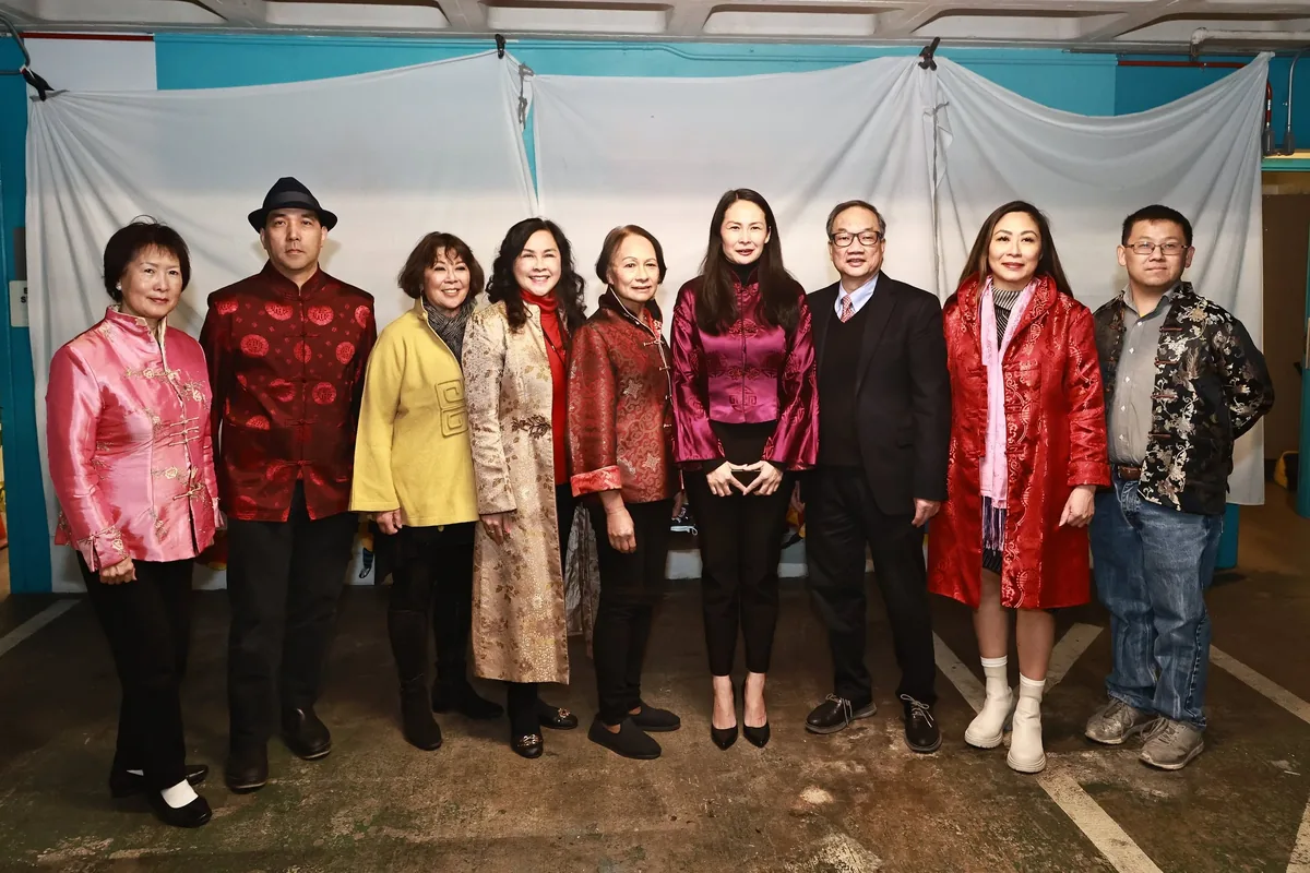 Nine guests in Lunar New Year attire stand in front of the curtained mural before its unveiling