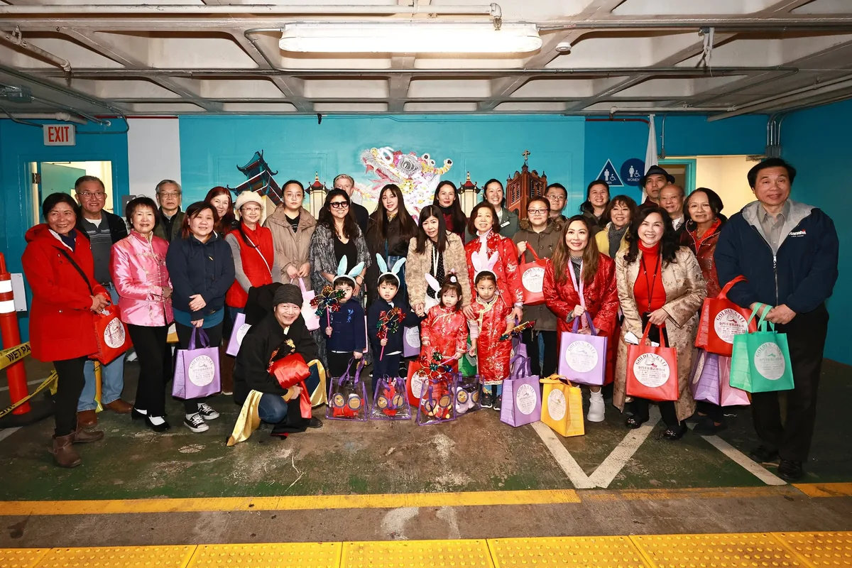 Guests holding gift bags pose in front of the mural at the unveiling celebration